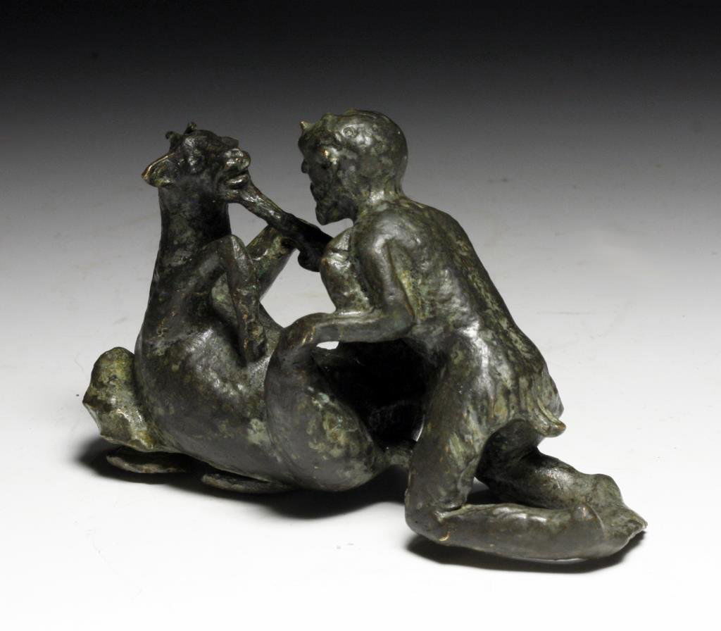 Greek Hellenistic Bronze Fitting of Pan & Goat: Greece / Bactria, ca. 320 - 300 BCE. Cast bronze figure of Pan engaging in sexual intercourse with a goat; with incised facial and body detail. Base has four attachments for mounting on a piece of fur