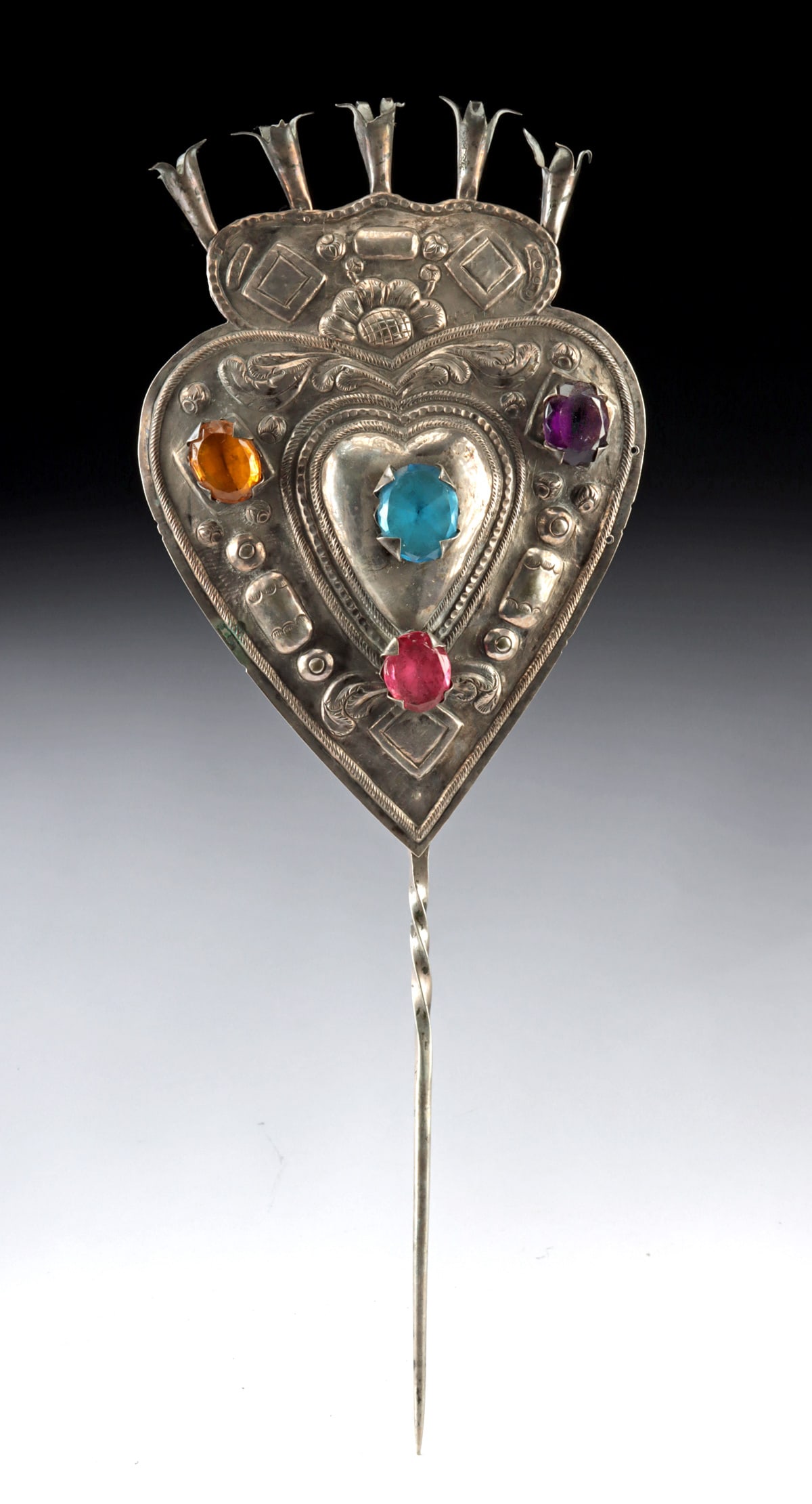 Large Bolivian Heart Shaped Silver Tupu w/ Glass Inlays: South America, Bolivia, ca. 19th to early 20th century CE. A magnificent silver tupu pin with vivid semi-translucent faceted glass inlays set within a heart-shaped finial. The slender pin features a t