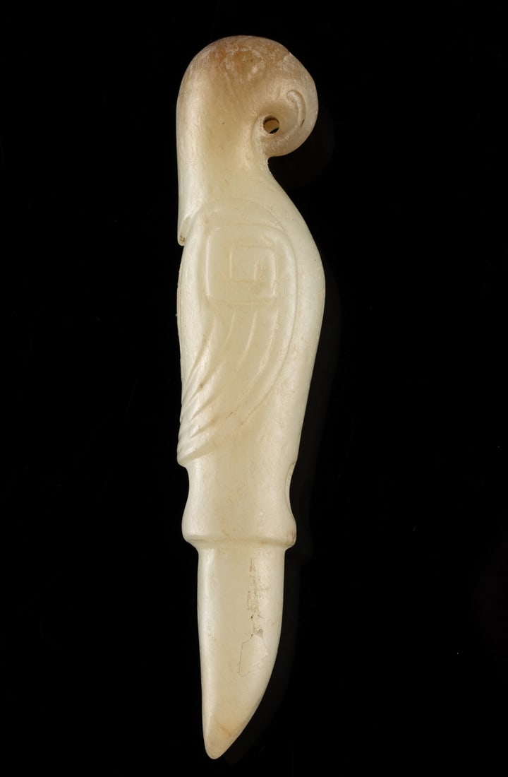 Chinese Archaistic Jade Parrot Pendant: East Asia, China, ca. 20th century CE. A carved parrot-form pendant rendered in revival archaic style. The stylized bird is shown in profile with a curved beak and elongated tail, the wings decorated 