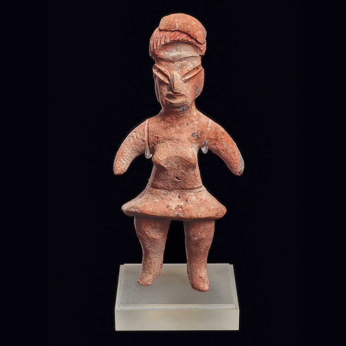 Tlatilco Standing Female Figure - Wrapped Hairdo, Red Pigment: Tlatilco. Ca. 1150 - 550 BCE. Buff-brown solid pottery standing female figure, depicted bare breasted and wearing a short skirt. Wrapped hairdo with incised detailed bangs. Some traces of red pigment 