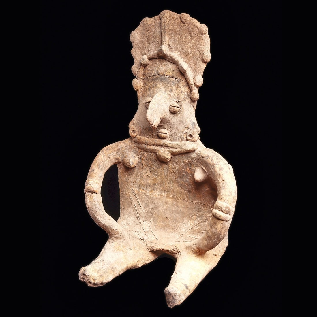 Colima Large Gingerbread Female Figure: Colima. Ca. 100 BCE - 250 CE. Large buff color pottery seated female figure, with long curved arms holding both hands on her lap. Wearing a tall hairdo or headdress decorated with ball elements. Depic