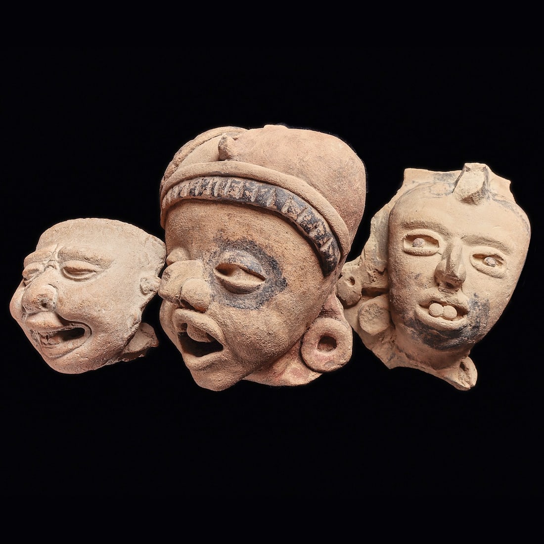 Veracruz Pottery Heads (3): Veracruz. Ca. 600 - 900 CE. Three different hollow pottery heads, all originally from figures. The smallest head is from a Sonriente type figure of unusual style, having extremely expressive facial fe