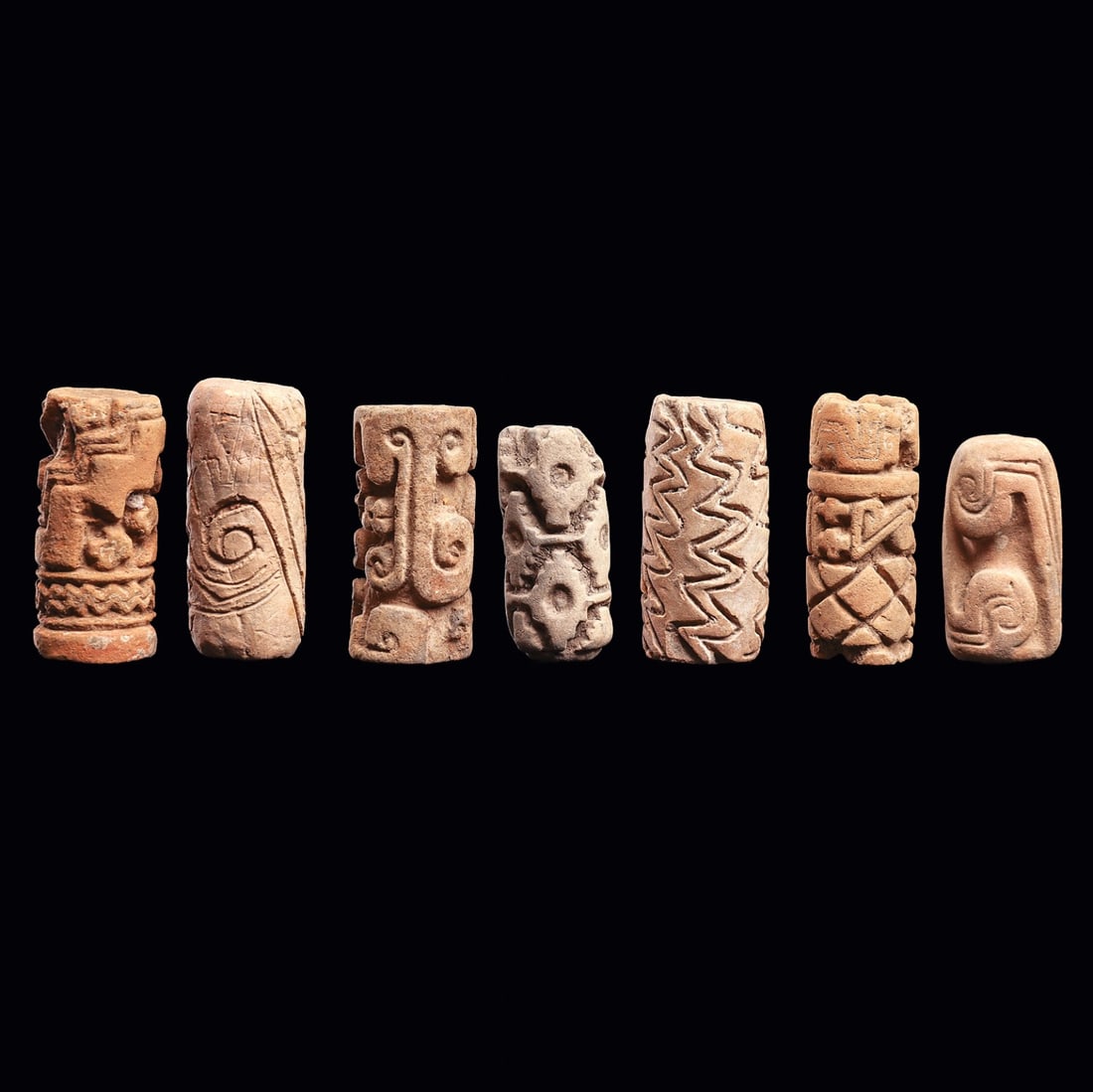 7 Ecuadorian Roller Seals, Carved Geometric Designs: Ecuador. Ca. 500 - 1000 CE. Group of seven different pottery roller seals, all having deeply carved designs with various geometric design elements. All have some edge chips and imperfections, otherwis