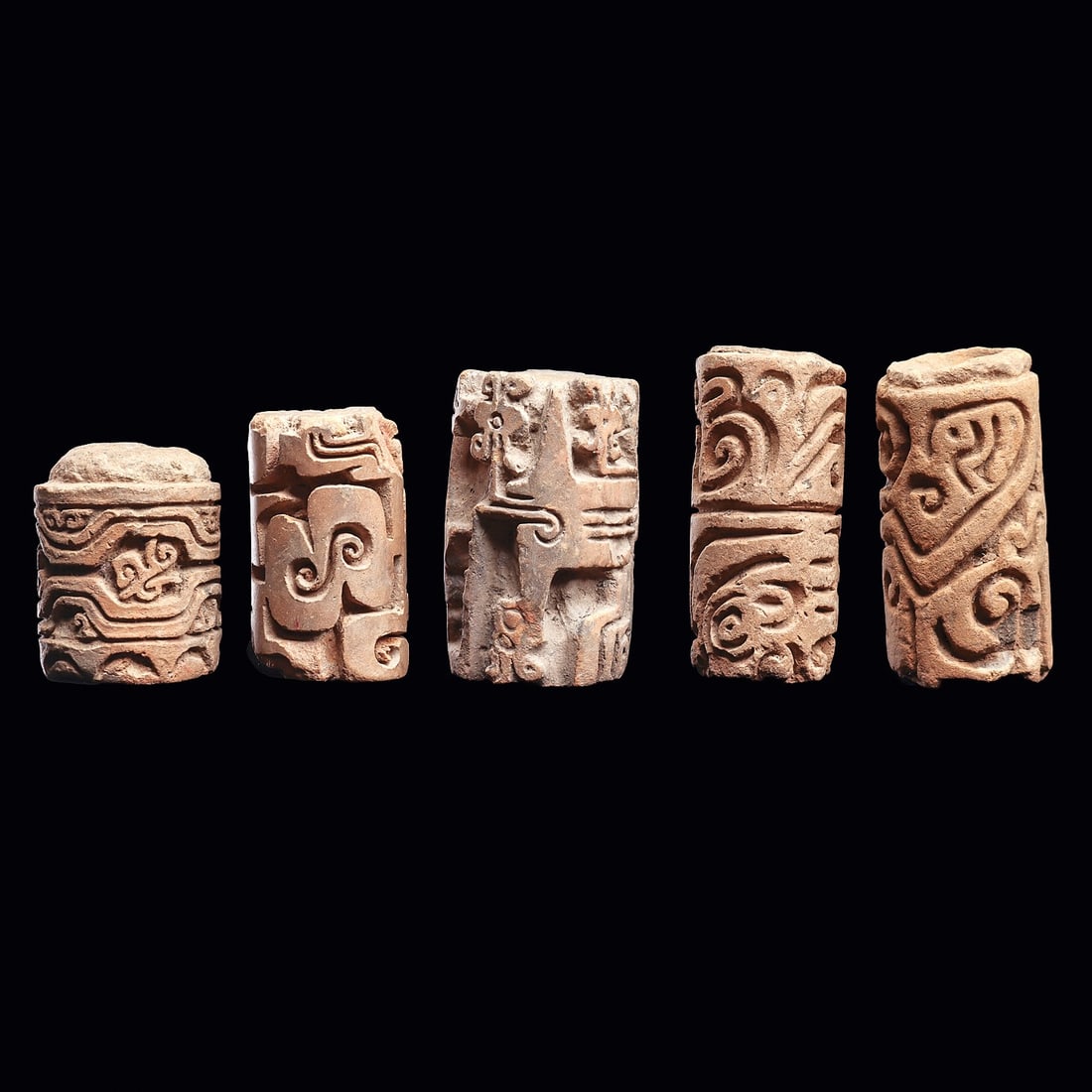 Ecuadorian Roller Seals (5): Ecuador. Ca. 500 - 1000 CE. Group of five different larger pottery roller seals, all having deeply carved designs with various geometric design elements, and animals. Two have some upper and lower edg