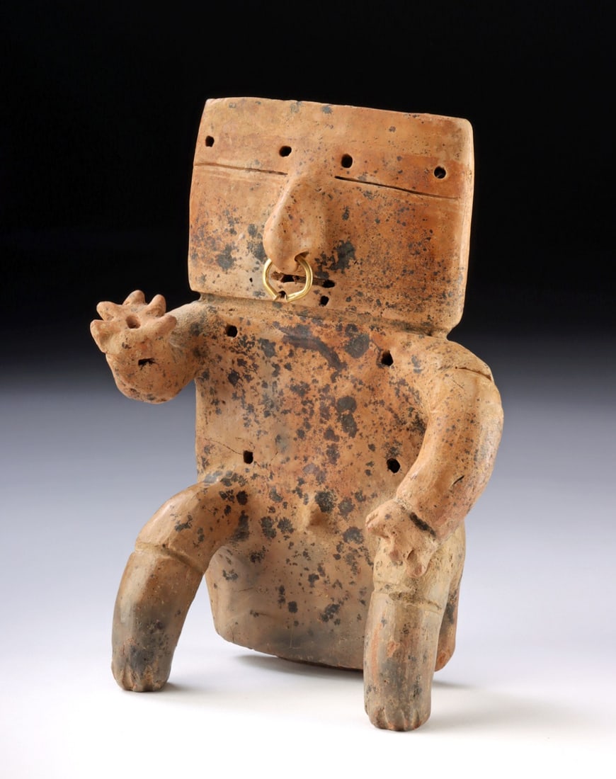 Quimbaya Seated Male Pottery Figure with Gold Nose Ring: re-Columbian, Colombia, Quimbaya culture, ca. 11th to 15th century CE. A hand-built pottery slab figure, seated on a broad posterior with tubular limbs - one arm bent and hand raised as if holding a v