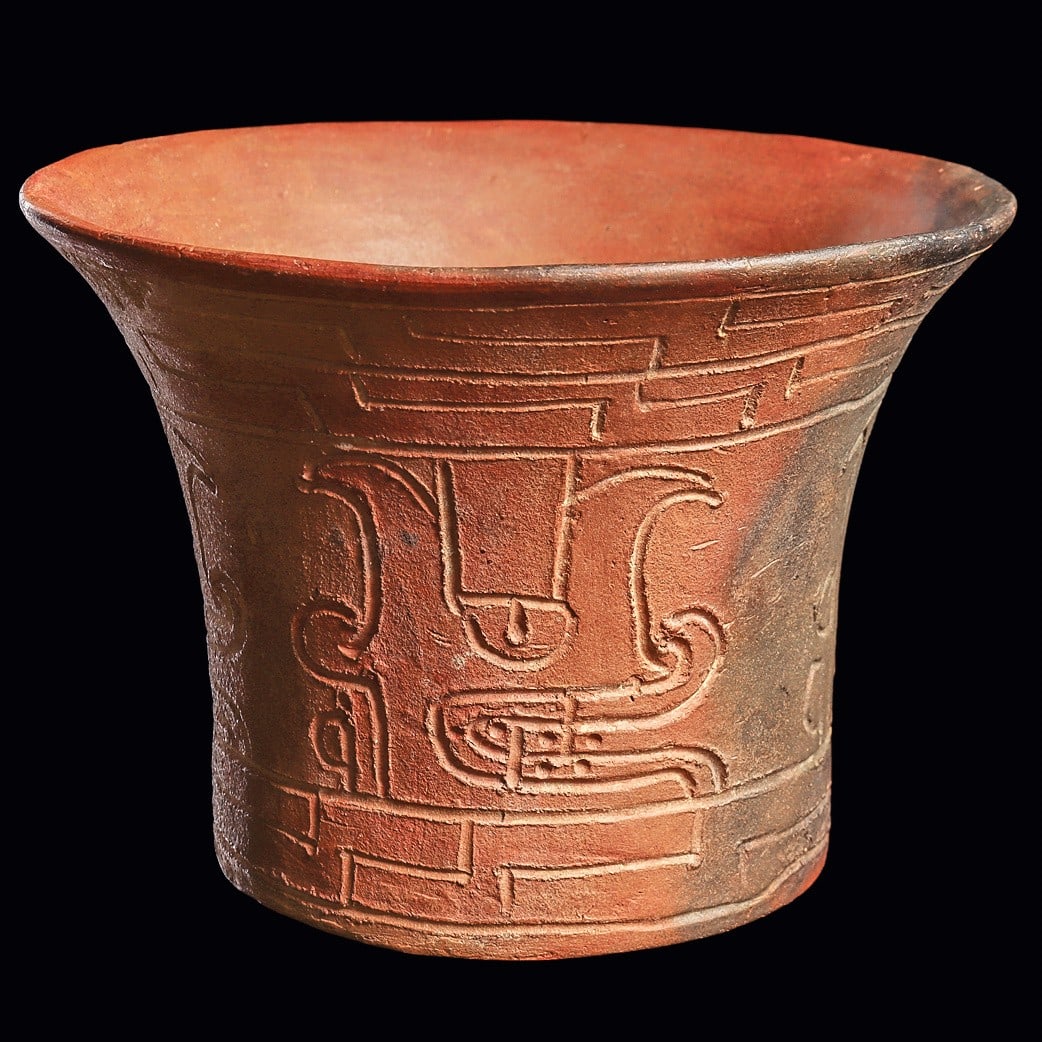 Chavin Flared Rim Vessel - Incised Deity Heads: Chavin. Ca. 1200 - 500 BCE. Salmon color pottery flared rim vessel having an incised decoration including a wide center band with four large profile deity heads. Upper and lower interlocking stepped