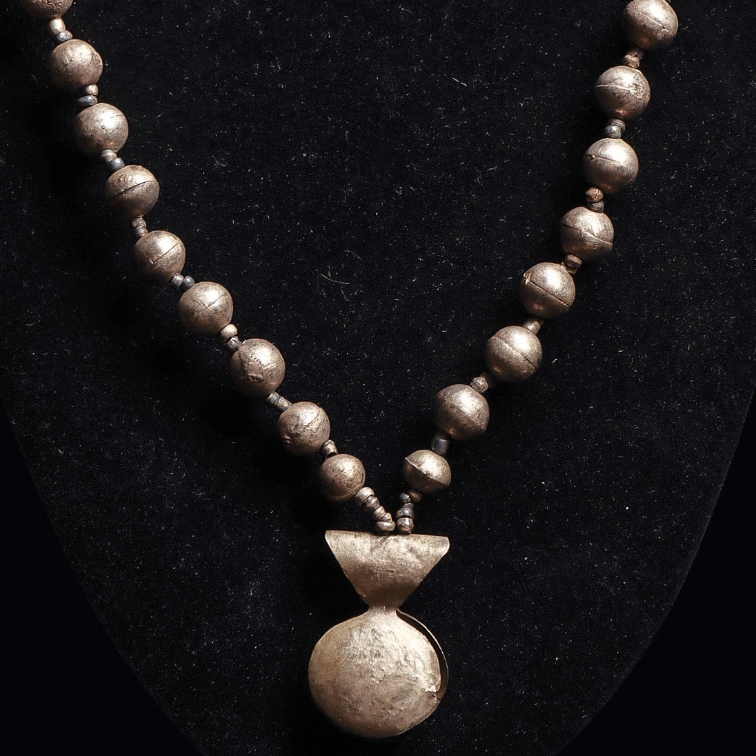 Chimu Silver Necklace With Depilatory Tweezer: Chimu. Ca. 1000 - 1250 CE. Single strand silver graduated ball bead necklace with a silver depilatory tweezer as a center piece. The silver beads are of two piece molded construction. Modern strung