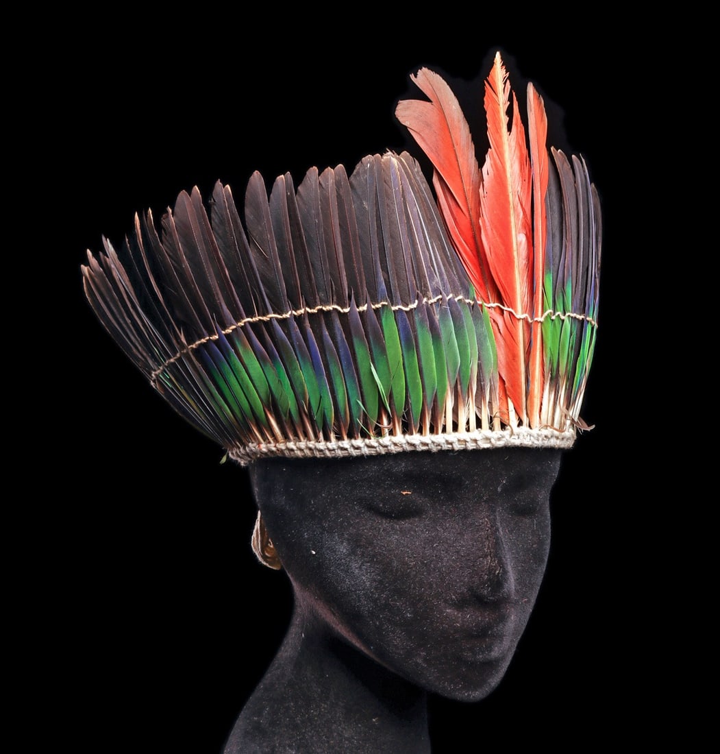 Amazonian Feathered Headdress: Amazon. Mid 20th century. Headdress composed of mostly green and dark brown long Caique feathers with two red-orange Macaw feathers in the center. All set in a woven cotton string head band with strin