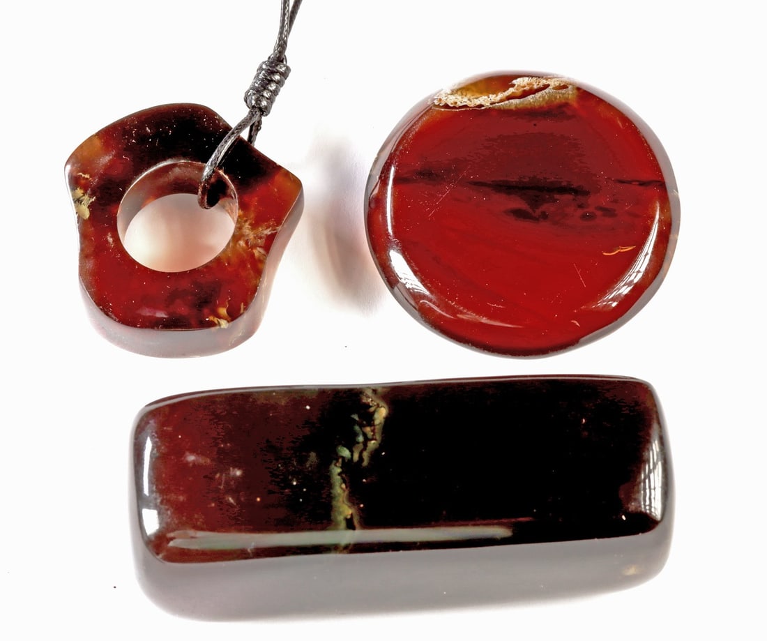 Sumatran Polished Amber Pendant, Disc, & Prism, 3: Southeast Asia, Indonesia, Sumatra, ca. 20th to 21st century CE. A lot of three polished Sumatran amber objects comprising a quatrefoil-form pendant with a drilled central aperture suspended on a brai