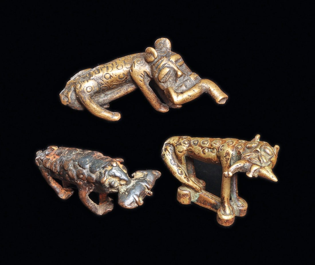 Goldweight Leopards with Prey (3): Ghana. These rare Ashanti goldweights of similar form communicated proverbs of stealthiness and achievements associated with leopards. One leopard holds a leg while lounging with tail tucked under. On