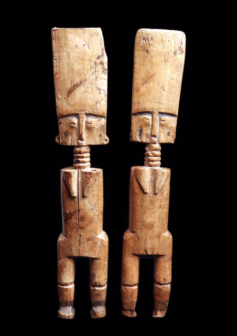 Pair of Fanti Fertility Dolls: Ghana. Matching dolls carved of blonde wood, with distinctive long rectangular heads with engraved pattern on back, one with pyro-engraved blackened pigment. Delicate scarification marks on torso,