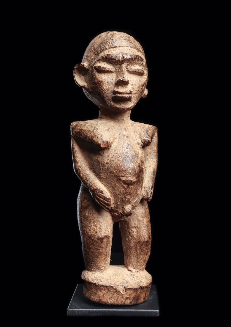 Lobi Figure: Burkina Faso. Carved wood male “bateba” figure with well defined elements, having full rounded head, wide torso with bulging abdomen, relief pectorals, and rising from cylindrical integral