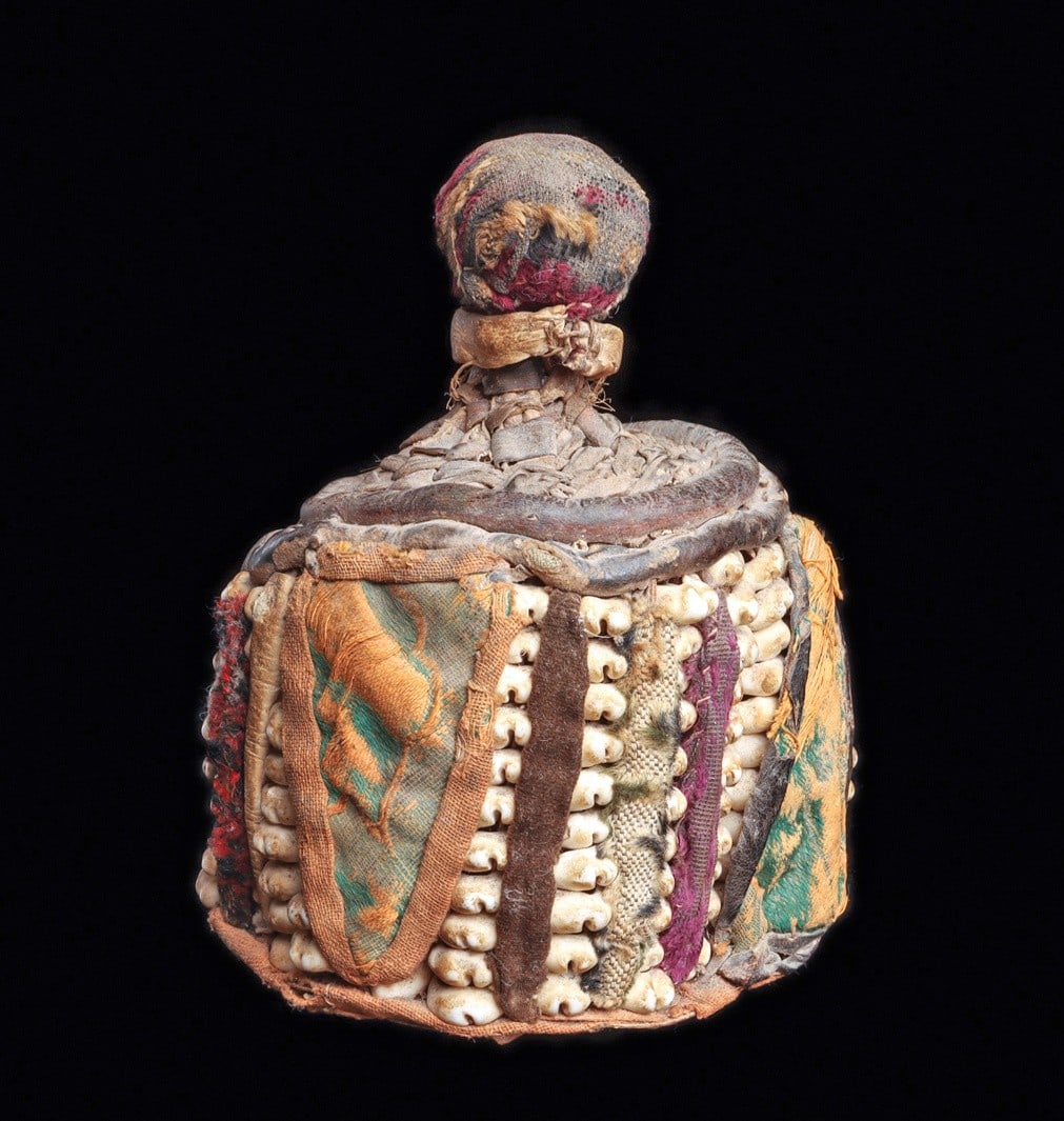Yoruba “Ipori”: Nigeria. Small altar container representing the “altar of the head”, the cylindrical sculpture of fabric, woven leather strips is encircled with strands of stacked cowry shells, colorful f