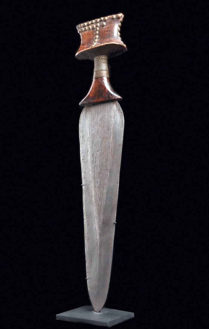 Kuba Knife with Metal Tacks: Democratic Republic of Congo.Fine prestige knife with metal tacks at flared butt, grip covered with braided metal strip, and long bifacial iron alloy blade engraved with linear pattern. Few tacks