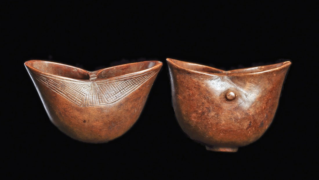 Suku Cups (2): Democratic Republic of Congo. Both “kopa” wood cups of organic curved form, with rounded body having pinched rim in center to form bi-lateral spout openings. One with varied cross-hatched 