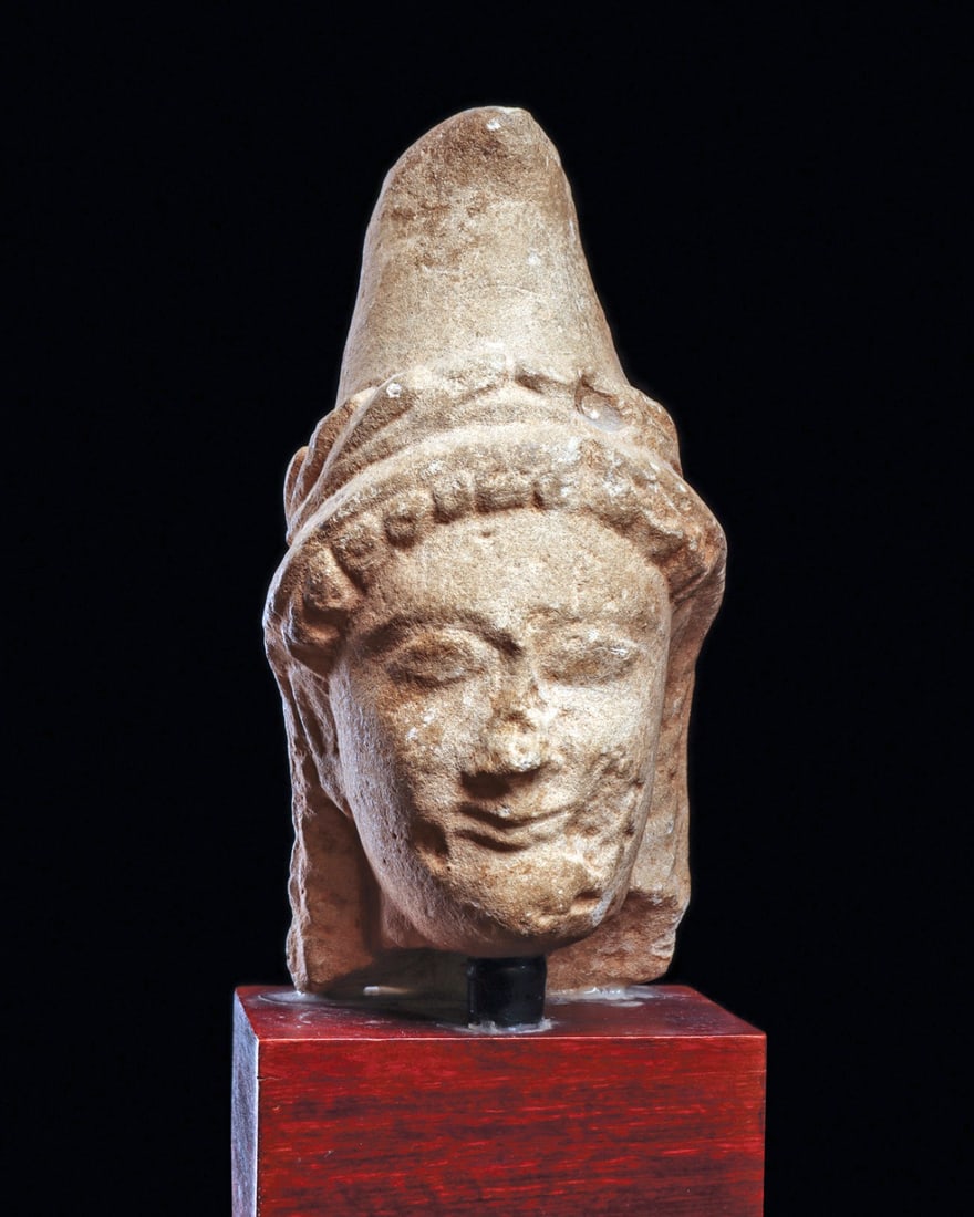 Cypriot Limestone Head: Cyprus. Hellenistic period, ca. 4th to 3rd century BCE. Carved limestone head, originally from a votive figure, possibly depicting Artemis Bendis, goddess of the hunt. Wearing a wreath on her phrygian