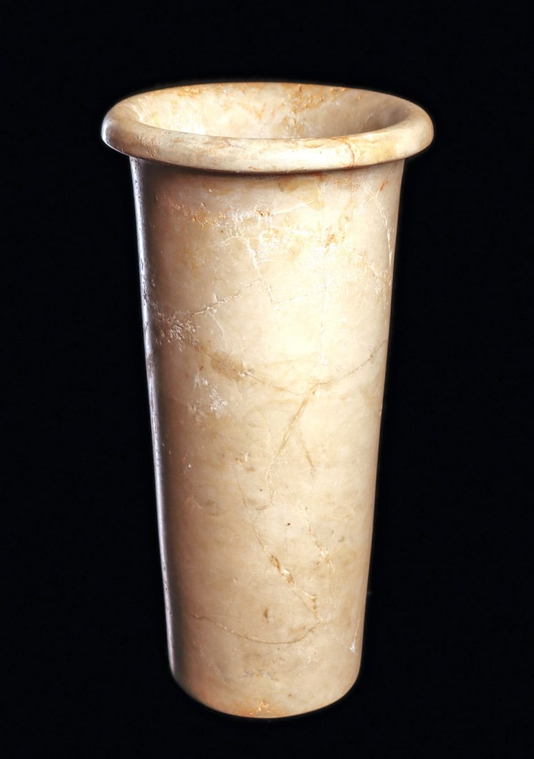 Egyptian Early Dynastic Alabaster Cylindrical Jar: Egypt. Early Dynastic Period, ca. 2750 - 2649 BCE. Carved alabaster tapered cylinder vase, having a round lip rim. Fine circular drill lines on the interior. Very cleanly repaired from approximately t