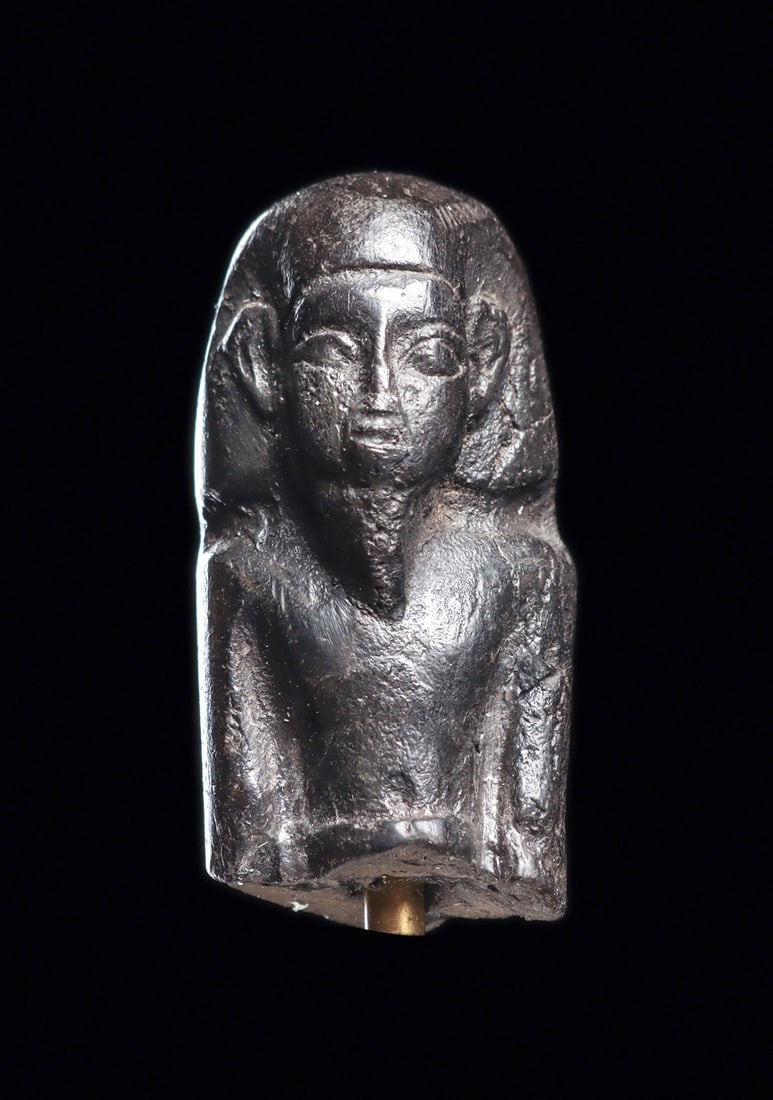 Egyptian Mummiform Ushabti Bust: Egypt. Middle to Late periods, ca. 1000 - 500 BCE. Molded blackware pottery upper portion of a ushabti, depicted wearing the royal wig and beard, arms held to his sides, bare chested, with a belt on h