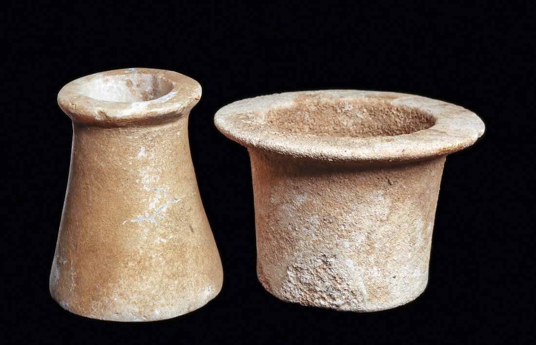 Bactrian Alabaster/Marble Vessels (2): Central Asia.Ca. 2nd - 1st millennium BCE. Two different carved white marble small vessels, including a short cylindrical example having a wide flat rim. Overall heavily encrusted surface patina and a