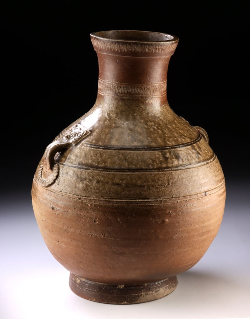 Tang Dynasty Glazed Pot with Taotie Handles - TL Tested: Far East, China, Tang Dynasty, ca. 618 to 907 CE. High-fired stoneware jar rises to a tall collared neck with crisply rouletted chevron bands and bears two strap handles issuing from an archaistic tao