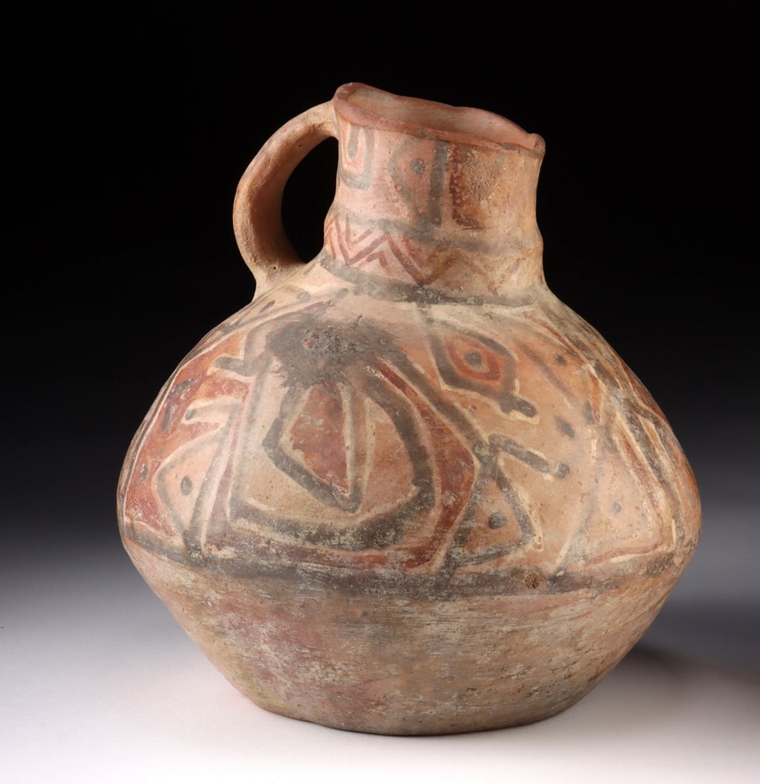 Tiwanaku Polychrome Jar with Handle: Pre-Columbian, South America, Bolivia/Peru, Tiwanaku culture, ca. 500 to 1000 CE. A robust globular jar of hand-built earthenware, its swelling body encircled by a program of polychrome geometric orna