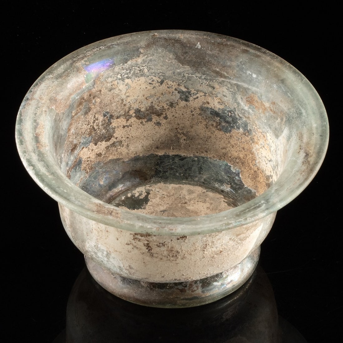 Roman Glass Footed Bowl: Roman, Imperial period, ca. 1st to 3rd century CE. An attractive bowl free-blown from translucent light green glass to present a rounded bottom and a wide-flaring rim, all sitting upon a discoid foot.
