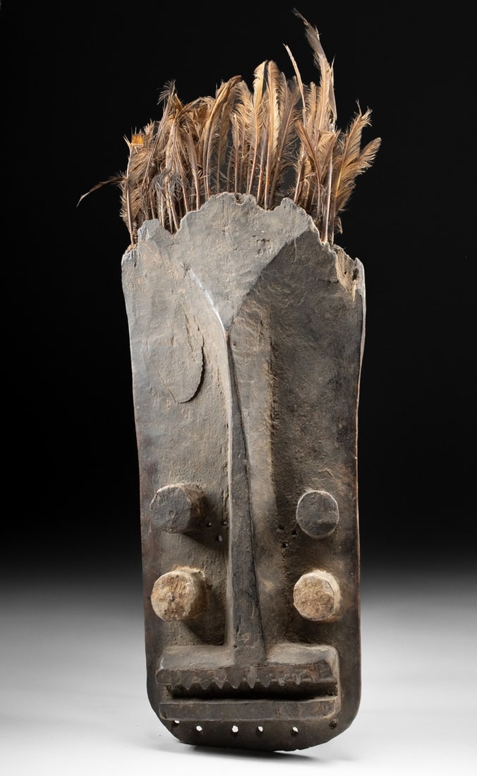African Grebo Abstract Wood Mask with Feathers: West Africa, Liberia / Ivory Coast border region, Grebo people, ca. early to mid-20th century CE. A striking Grebo face mask carved from a single piece of dense wood, characterized by its bold geometr