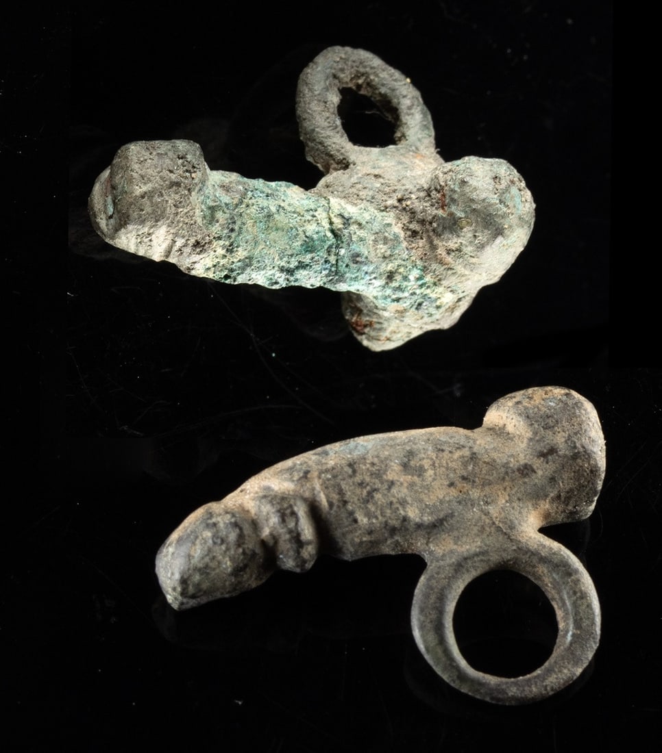 Two Roman Bronze Fascinum Phallus Pendants: Roman, Imperial period, ca. 1st to 3rd century CE. A compact pair of Roman phallic ornaments, small in scale but enormous in intention, made to laugh in the face of bad luck. Known as fascinum (plural