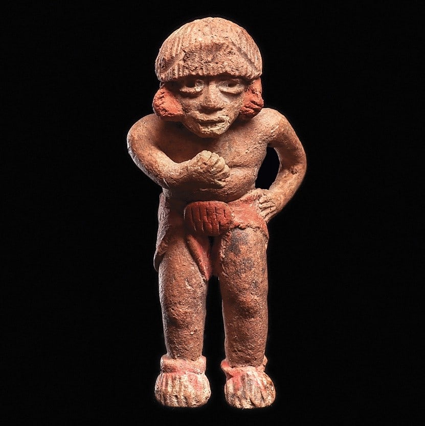 Xalitla Standing Male Figure: Guerrero region, ca. 1500 - 1000 BCE. Natural salmon-tan color solid pottery standing figure holding his left hand on his hip, right hand in front of his chest. Wearing a loincloth, slippers and ear o