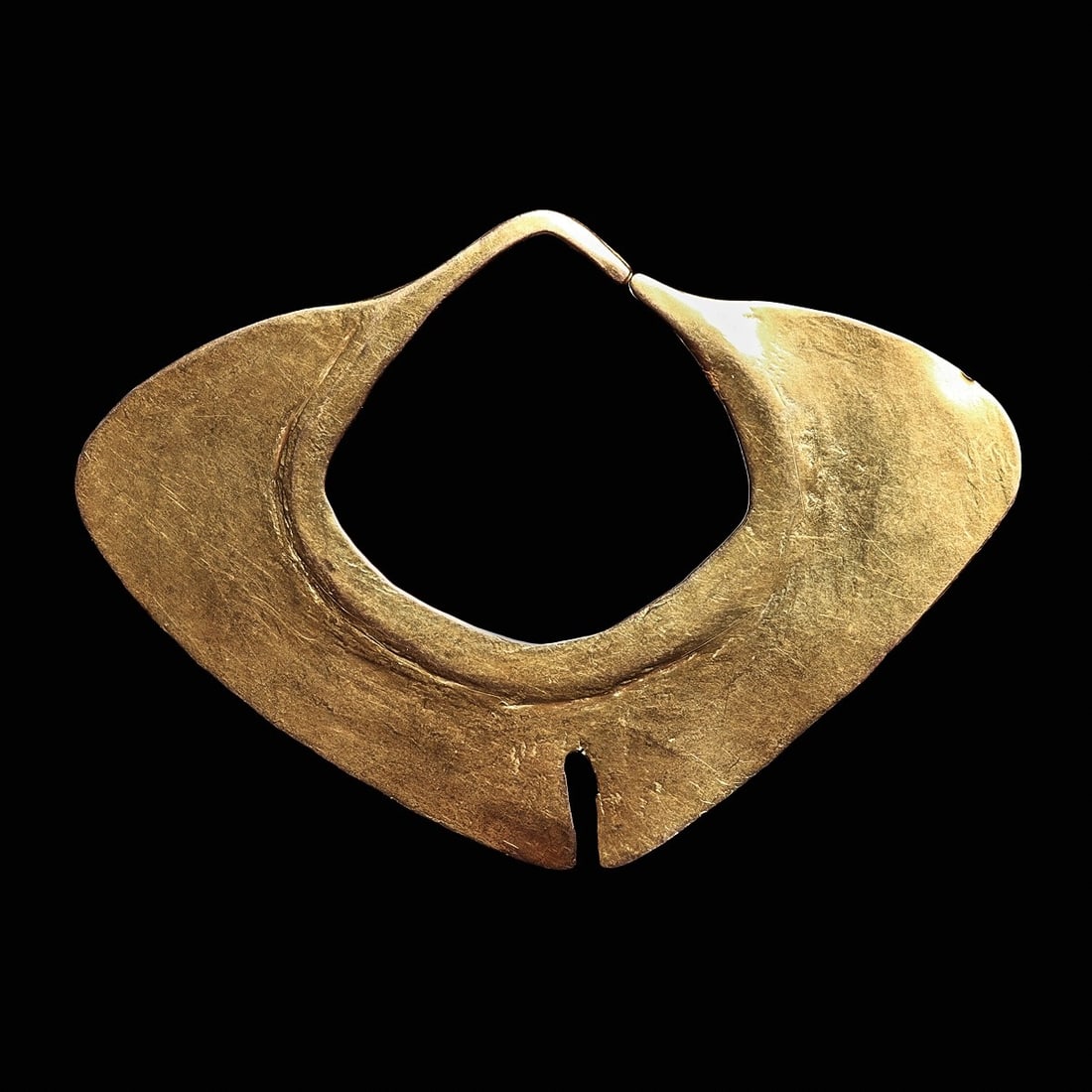 Tairona Gold Nose Ornament | Stylized Butterfly Wing Form: Tairona, Colombia, ca. 800 - 1425 CE. Large hammered gold nose ornament, of a stylized “butterfly” wing form, having a raised inner border opening to an angular openwork element, and termi