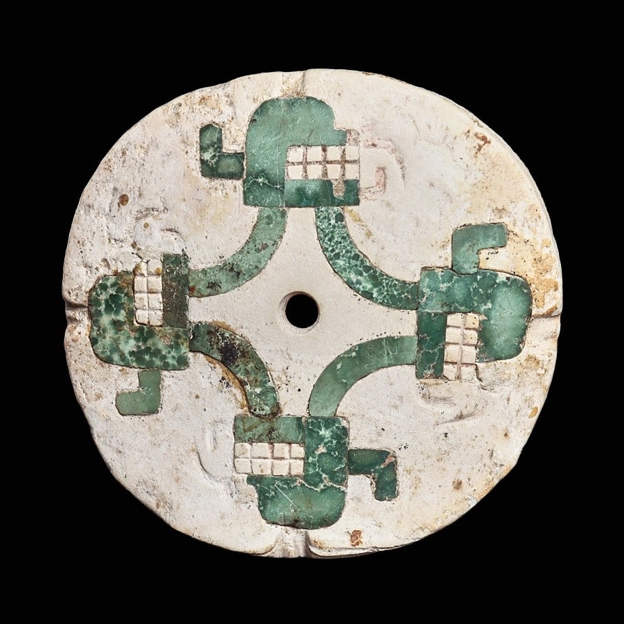 Chavin Shell & Inlaid Stone Ear Ornament: North coast, ca. 1200 - 500 BCE. Carved slightly concave shell disc ear ornament having finely inlaid mosaic mottled blue-green and turquoise color stone stylized trophy heads with inlaid shell toothy