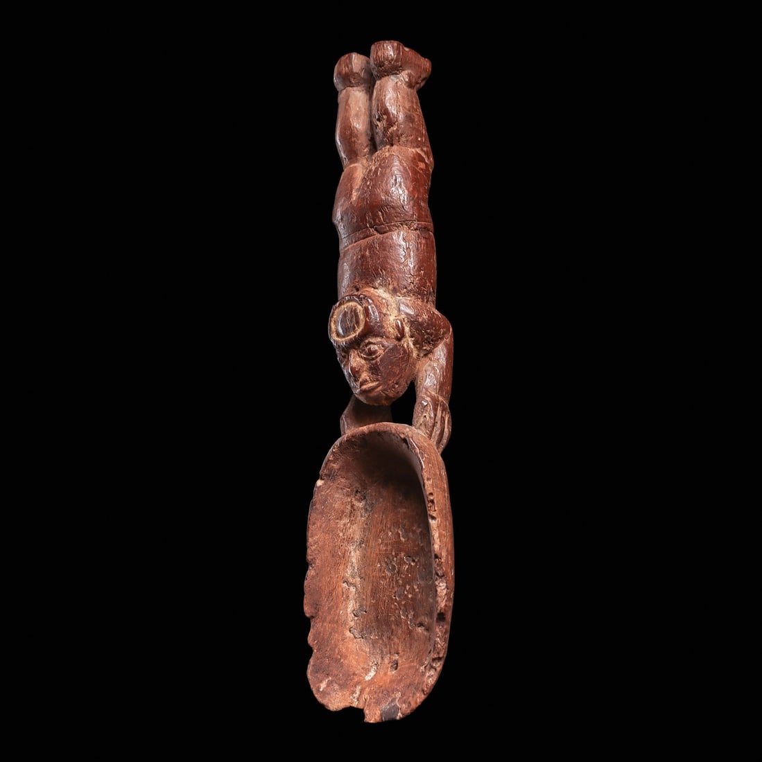 Moche Wooden Spoon Depicting a Flying Shaman: North coast, ca. 100 - 500 CE. Carved wooden medicine spoon depicting a flying shaman holding a large spoon bowl with both hands. The shaman’s head is looking in an upward position, and wearing 