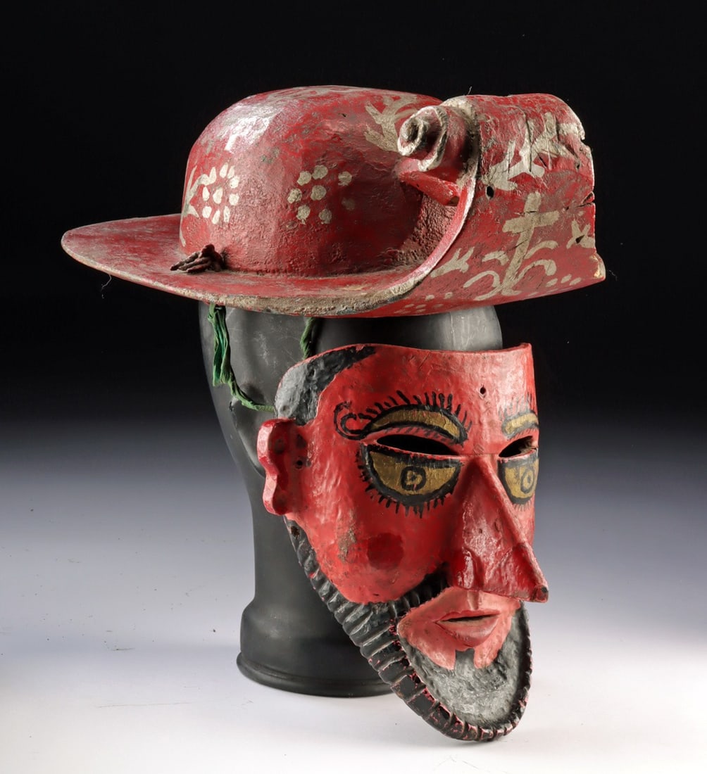 Vintage Mexican Wood Conquistador Mask & Helmet: Latin America, Mexican., ca. 1933 - 1966 CE. A blazing vermilion máscara de conquista depicting a bearded Spanish soldier, its heavy-lidded eyes with radiating lashes and gilt irises set beneath 