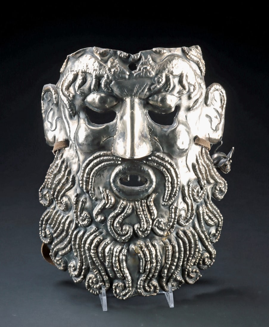 Mexican Silver Barbone Mask Pre-Columbian Bell, ex-Holler & Saunders: Latin America, Mexico, Guerrero., ca. 1900 - 1949 CE. A dramatic and finely worked example of a so-called "Barbone" mask, this silver visage merges European physiognomy with fantastical animal imagery