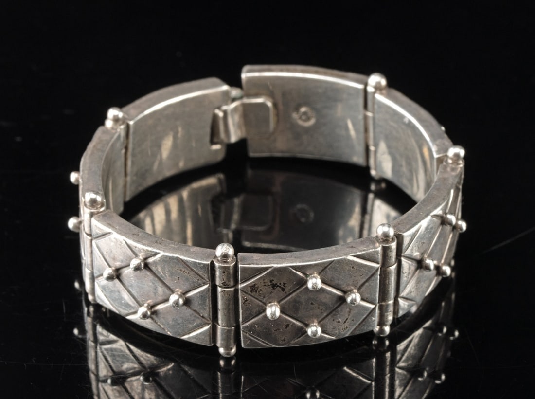 William Spratling Sterling Silver Articulated Panel Bracelet: Latin America, Taxco Mexico., ca. 1933 - 1966 CE. A sterling silver William Spratling bracelet composed of seven rectangular panels joined by hinges for articulated movement. Each panel is incised wit