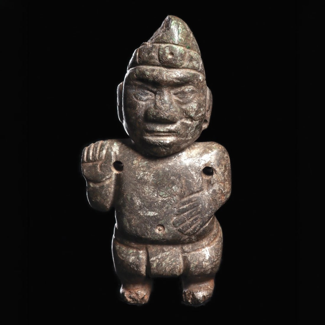 Olmecoid Serpentine Dwarf Shaman Figure: Olmec regions., ca. 1000–600 BCE. Carved serpentine standing dwarf shaman type figure, holding his left hand on his stomach and his right hand raised to his shoulder. Wearing a pointed cap with a