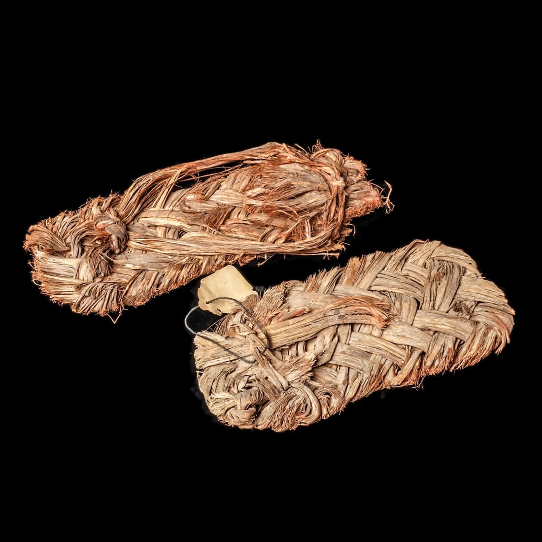 Anasazi Vegifiber Sandals (2): Southwestern USA, ca. 1000 - 1250 CE. Two possibly matched, very similar woven vegifiber sandals, each neatly woven with a partial tie ankle strap. Rare examples.. 8.5” (21.6cm) & 9.25”L
