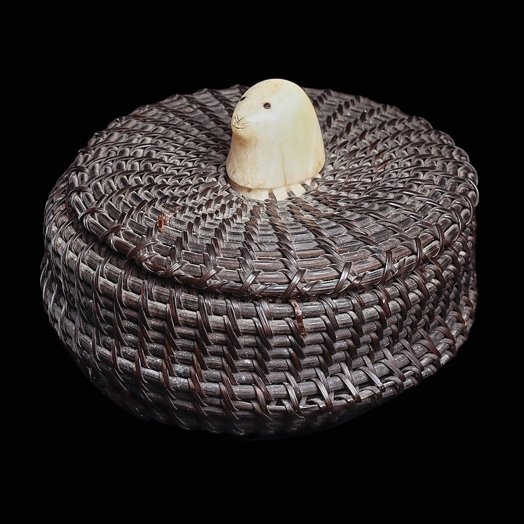 Eskimo Baleen Basket: Inupiaq Culture, Alaska, ca. mid 20th century. Vintage woven baleen lidded basket with carved walrus ivory seal head finial and a disc sewn in the base. According to Quintana Galleries: “Baleen 