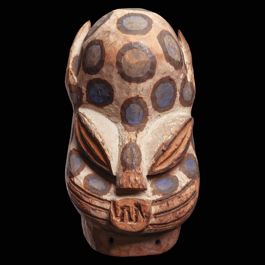 Bini Leopard Mask: Nigeria, . Carved wood mask of a leopard with rounded prominent forehead, feline ears, long ovate eyes above open eyeholes, rounded mouth with interlocking fangs, grooved whiskers, and the surface pai