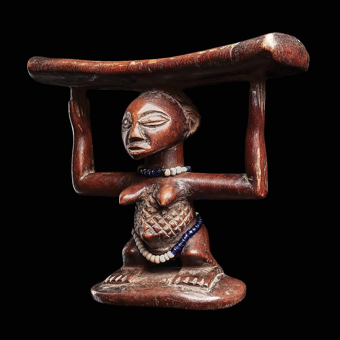 Luba-Hemba Headrest: Democratic Republic of Congo, . Supported by a carved female caryatid figure standing on broad, squared feet rendered in low relief. Her form displays characteristic Luba aesthetic ideals, including