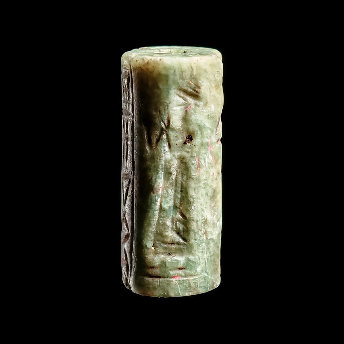 Old Babylonian Feldspar Cylinder Seal with Cuneiform Text: Mesopotamia, ca. 2000 - 1750 BCE. Bluish-green feldspar cylinder seal having a carved rollout impression depicting two standing dignitaries, both holding an offering (bird?) in their left hands, one f