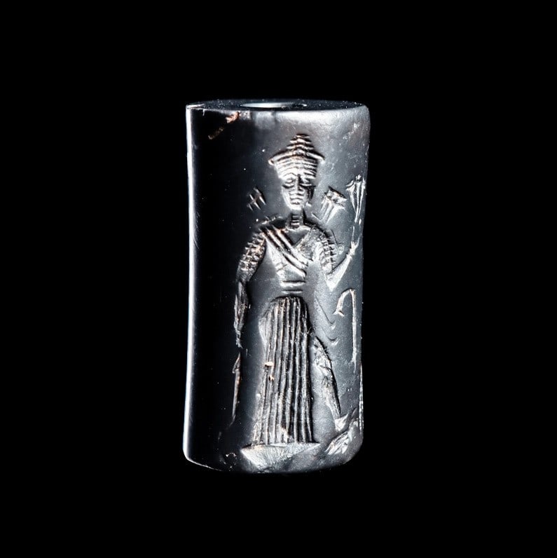 Old Babylonian Hematite Cylinder Seal: Ancient Near East. Mesopotamia, ca. 1900 - 1600 BCE. Hematite cylinder seal having a carved rollout impression depicting the frontally facing goddess Ishtar with her foot on her lion attribute, weapon