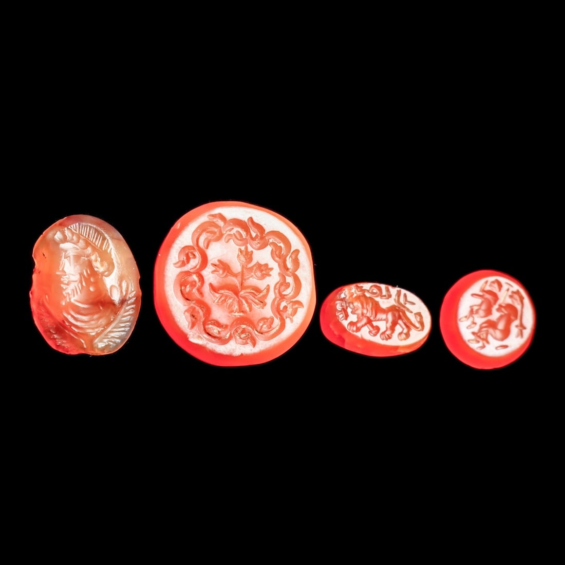 Sasanian Carnelian Intaglios (4): Sasanian Empire. Western Asia, ca. 5th - 6th century CE. Group of four different red-orange carnelian examples, including a round disc inset having a carved impression depicting a flowering plant in