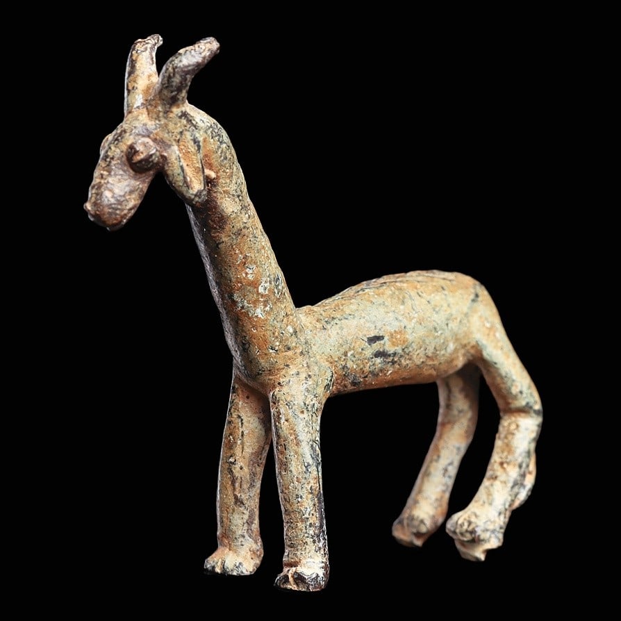 Luristan Bronze Goat: Ancient Near East, ca. 1st millennium BCE. Solid cast bronze standing goat, having curved horns and floppy ears, long neck and incised with a v-shaped mane down his neck and back. A very nice example.