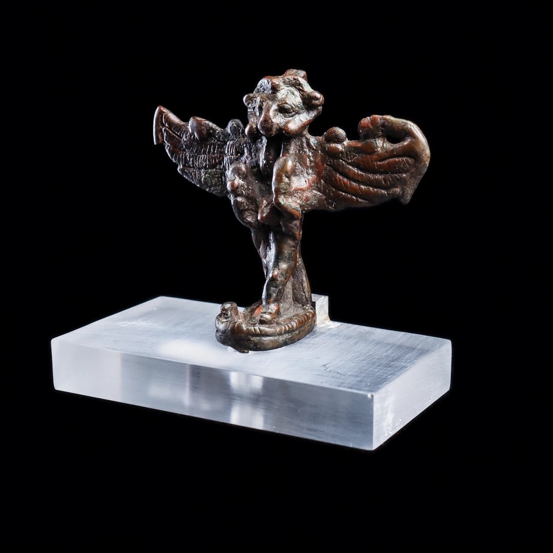 Greco-Egyptian Khnum Bronze Figure: Egypt, late period, ca. 700 - 400 BCE. Solid cast bronze depicting the ram-headed god Khnum, god of fertility and strength, having wide spread wings, and holding objects in both hands, tips of wings d