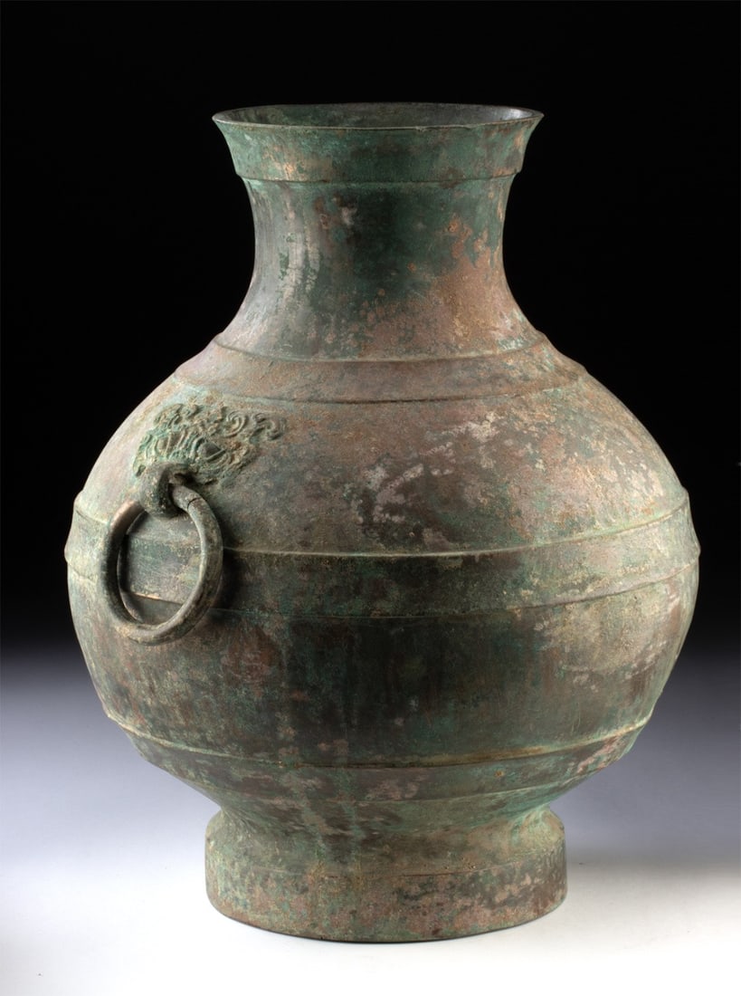 Chinese Han Dynasty Bronze Hu Vessel, Taotie Mask Ring Handles: East Asia, China, Han Dynasty., ca. 206 BCE - 220 CE. An elegant, pear shaped hu vessel, the iconographic program of this piece comes to life with two taotie masks that are affixed with ring handles o