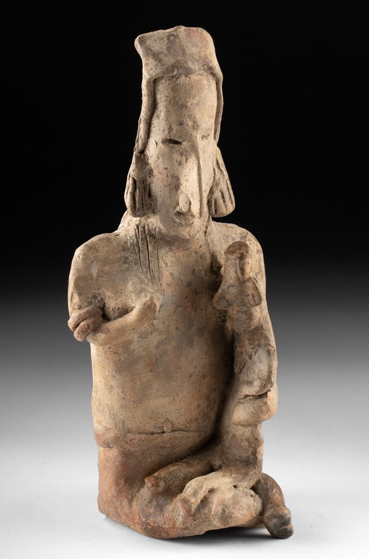 Ancient Jalisco Mother with Child Pottery Figure: Pre-Columbian, West Mexico, Jalisco, ca. 300 BCE to 300 CE. A hollow pottery figural effigy depicting a seated mother and child, formed in red clay and finished with a pale white slip, characteristic 