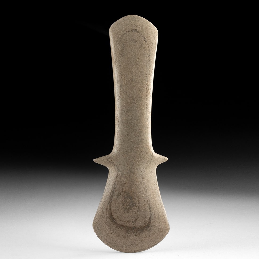 Mississippian Stone Ceremonial Mace: Native American, Mississippian culture, ca. 1000–1500 CE. A monolithic ceremonial mace carved from a single block of dense gray stone, its silhouette flaring from a tapered cylindrical haft into