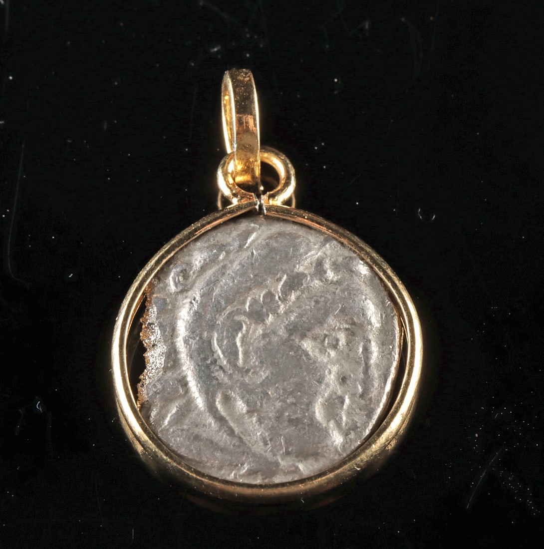 Greek Alexander the Great Silver Drachm in Gilt Pendant: Ancient Greece, Hellenistic Period, ca. 4th to 3rd century BCE. A striking ancient Greek silver drachm, now preserved within a modern gold-plated nickel pendant, uniting classical iconography with wea
