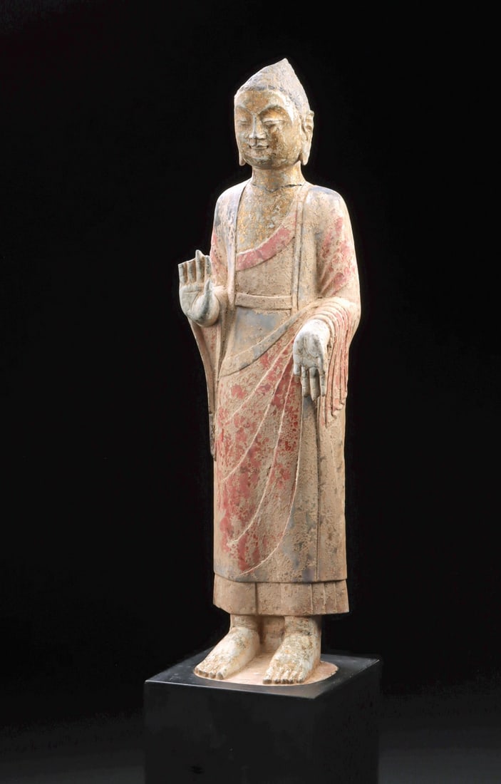 Qing Dynasty Stone Standing Buddha Figure: East Asia, China, Qing Dynasty, ca. 18th to early 19th century CE. A serene and dignified standing Buddha emerges in softly weathered stone, his presence at once tranquil and quietly commanding. The f